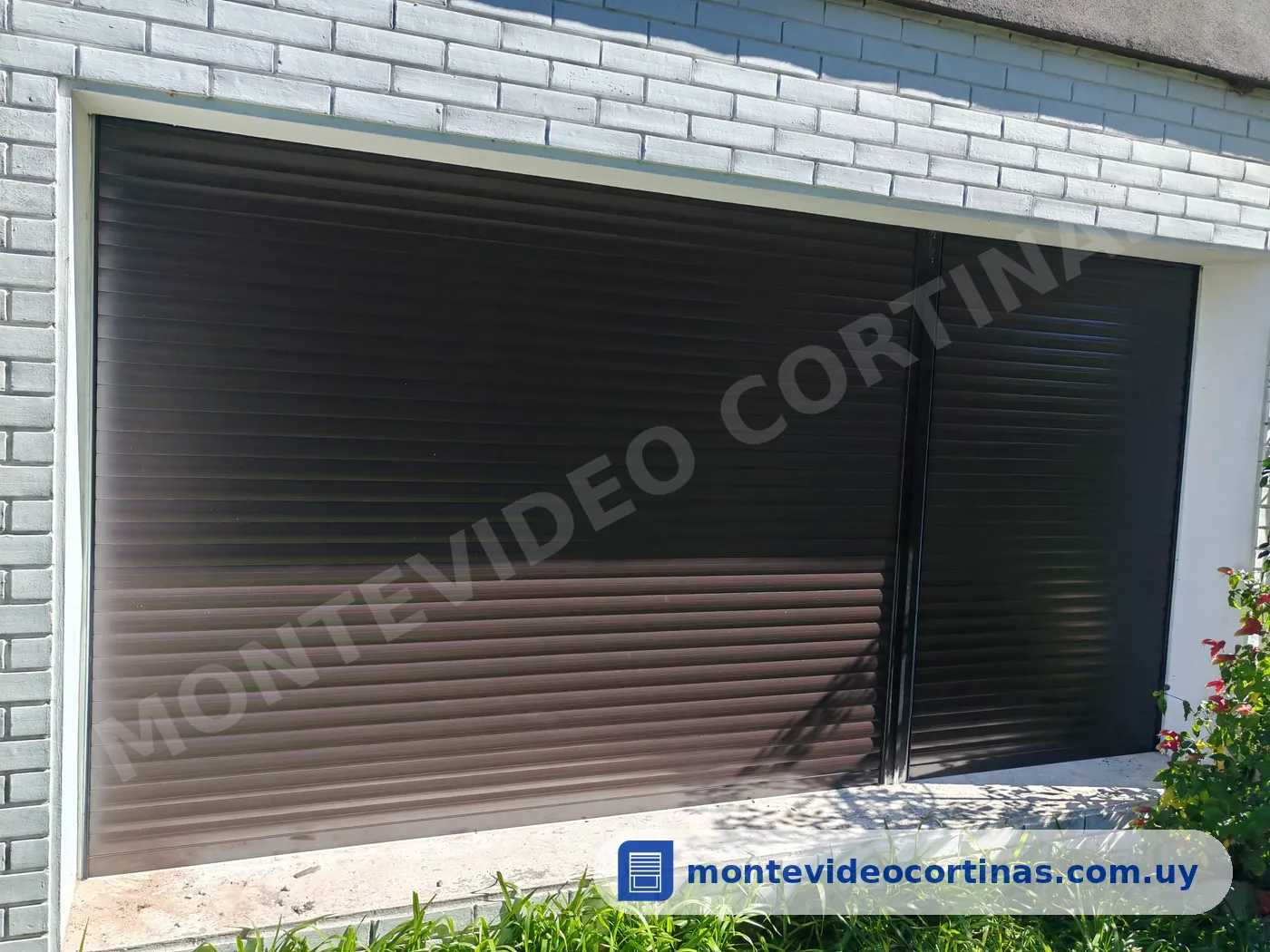 Cortina de enrollar oscura de gran ancho en una fachada blanca